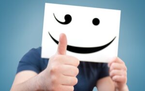 Suboxone addict hiding face behind a paper with smiley face.