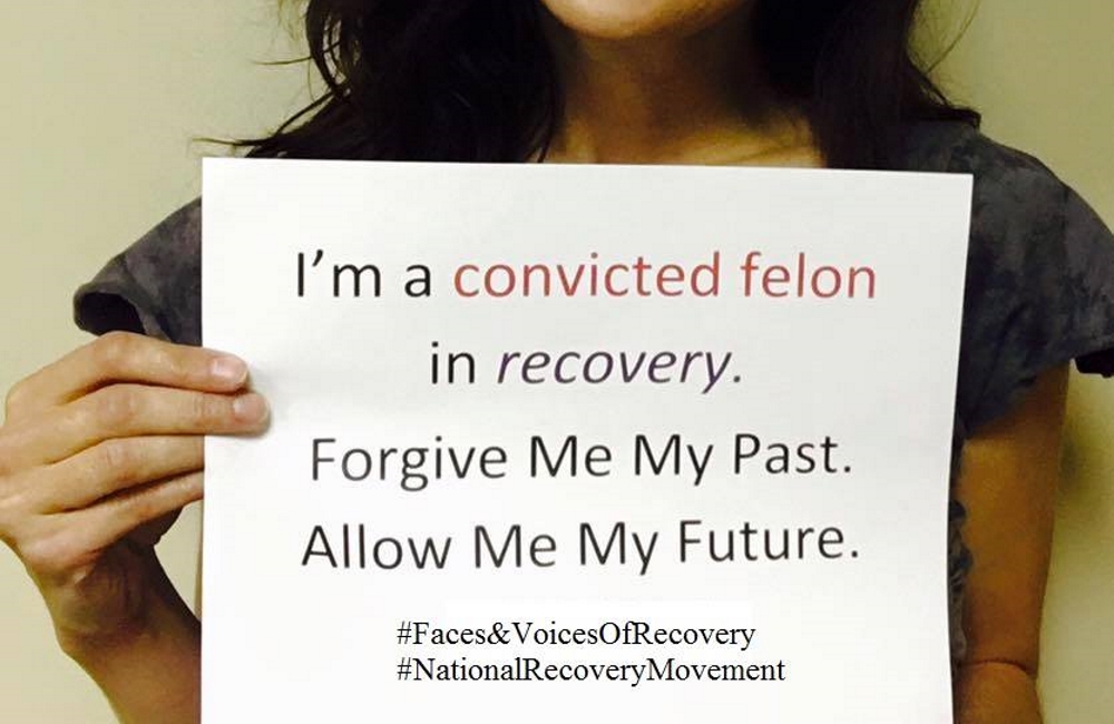 Woman holding sign that says "I'm a convicted felon in recovery. Forgive me my past, allow me my future."