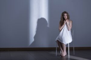 woman sitting no a chair alone in a dark room.
