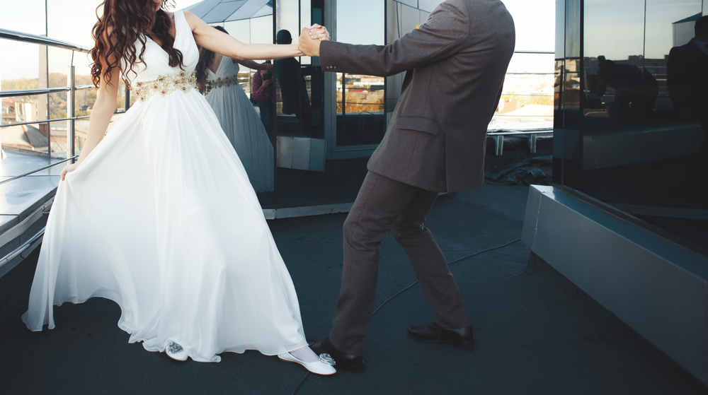 A couple in formal attire dancing, shown from the neck down.