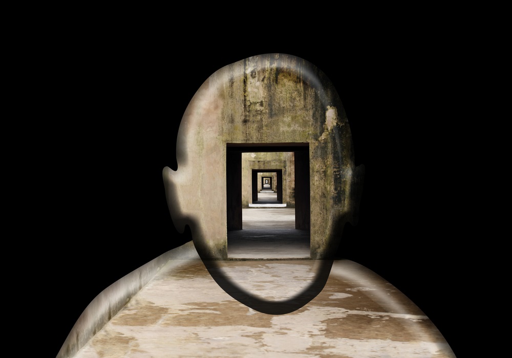 A wooden head-shaped form with a progression of doors in its center