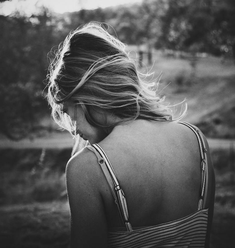 Woman with blondish hair standing with back to camera.
