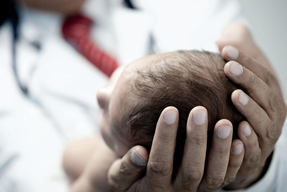 Doctor holding the head of newborn baby.