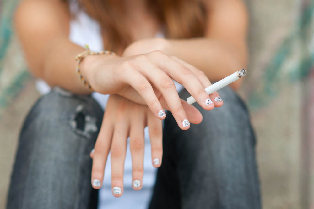 A woman's hands holding a cigarette.