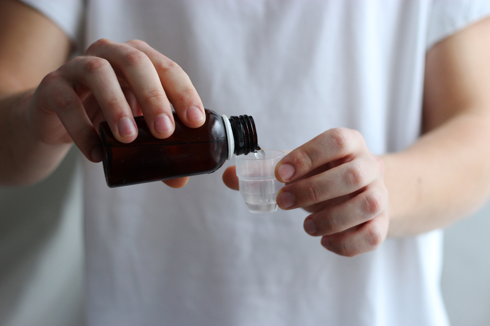 Cough medicine being poured into a medicine cup