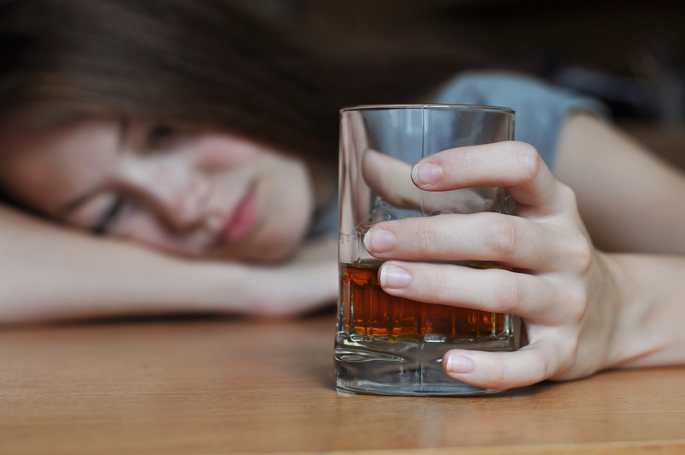 Girl drinking alcohol at table.