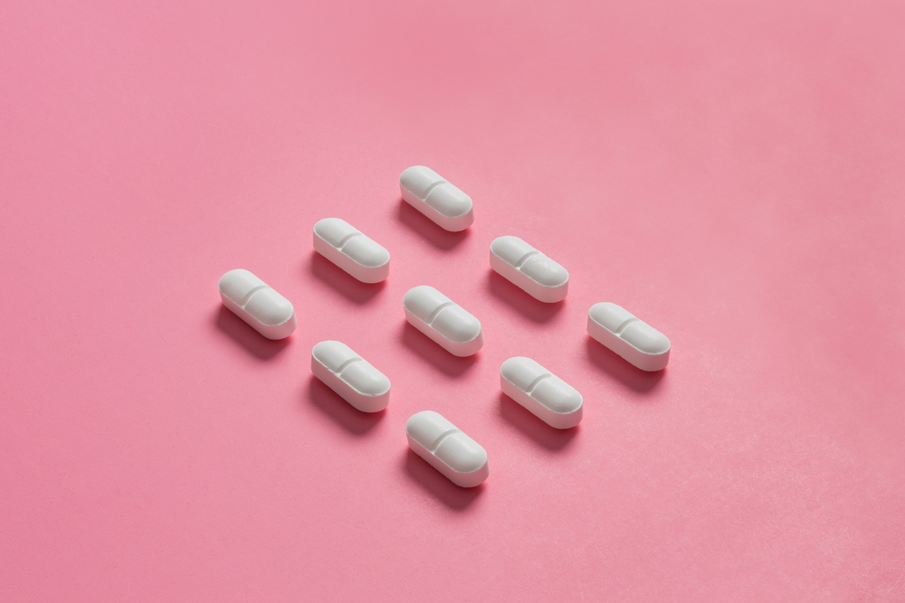 hydrocodone pills on a pink background.
