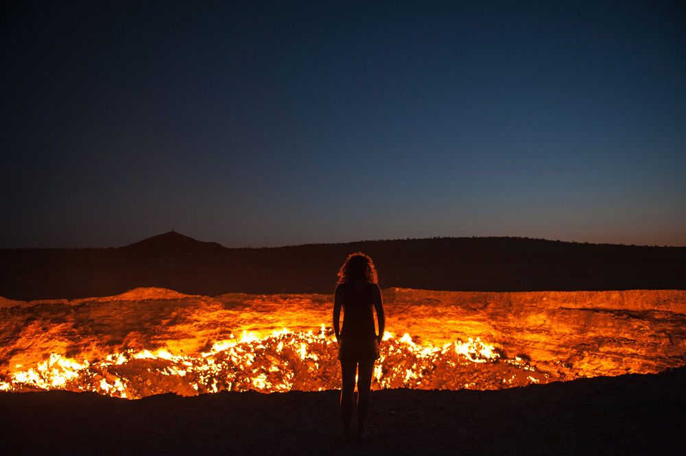 A person's silhouette in front of the top of a volcano or a giant pit of fire.