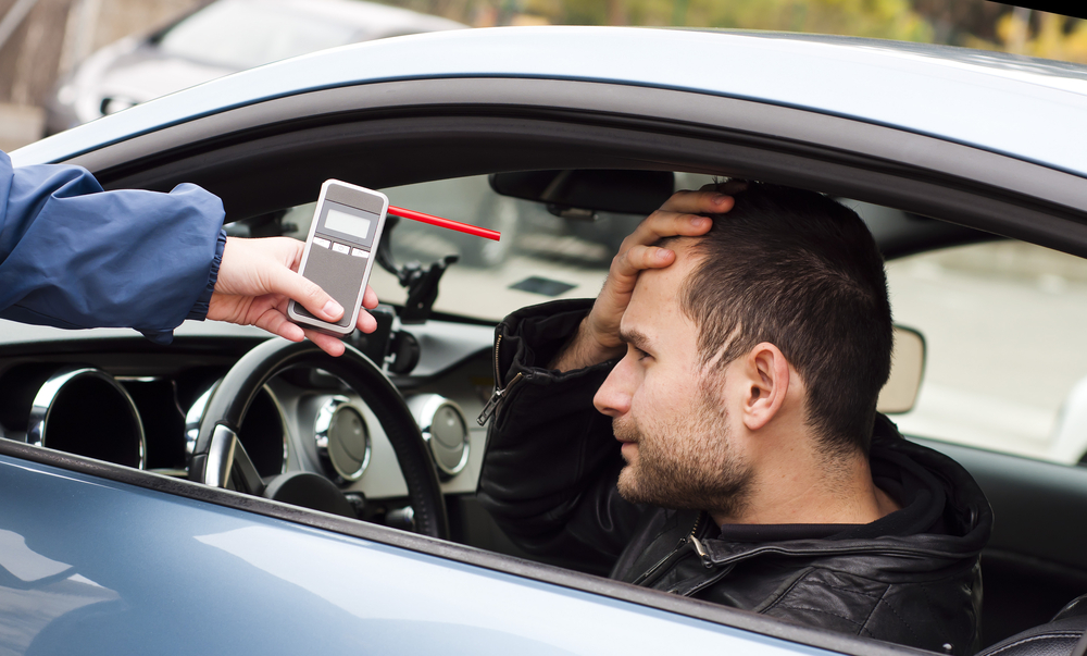 Officer giving driver breathalyzer test.