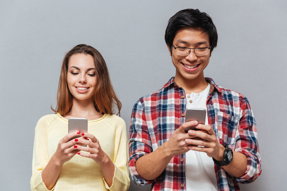 Man and woman looking at cell phones.