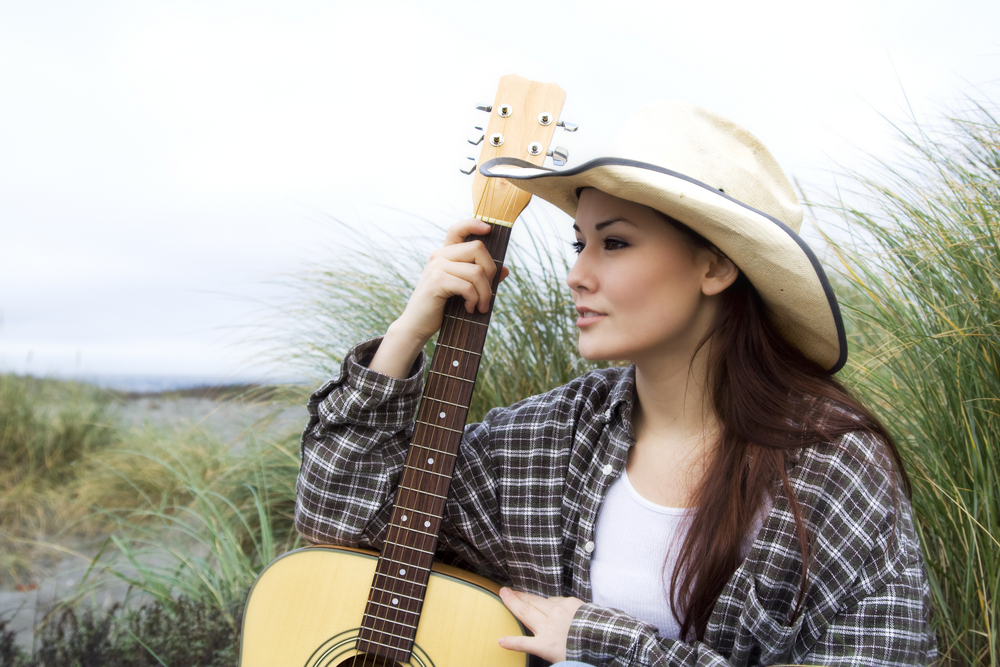 Woman in cowboy hat with guitar.