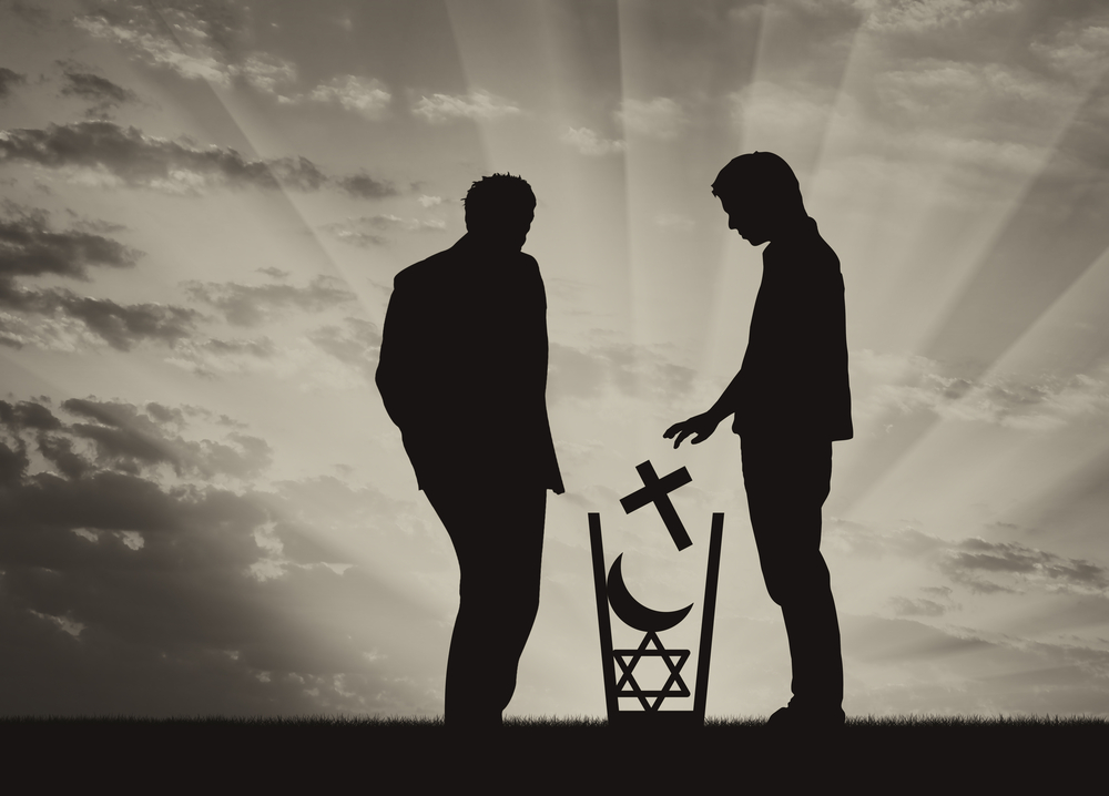 A silhouette of two people, one throwing religious symbols in the trash.