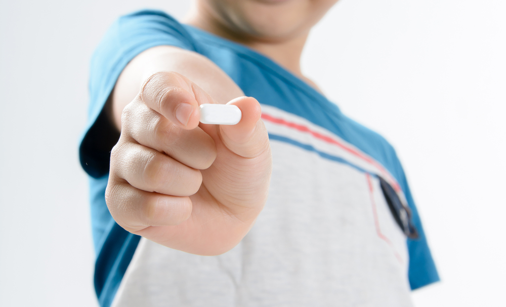 Young child holding pill.