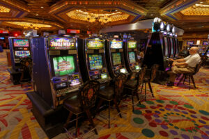 A row of slot machines in a casino with an elderly man sitting at the far end.