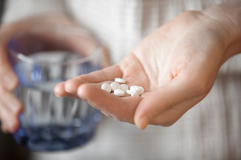 A person holding a handful of pills.