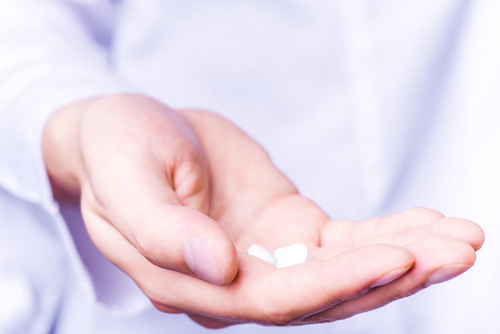 Person holding a handful of pills.