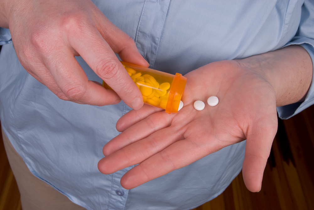 Woman taking pills from a prescription bottle.