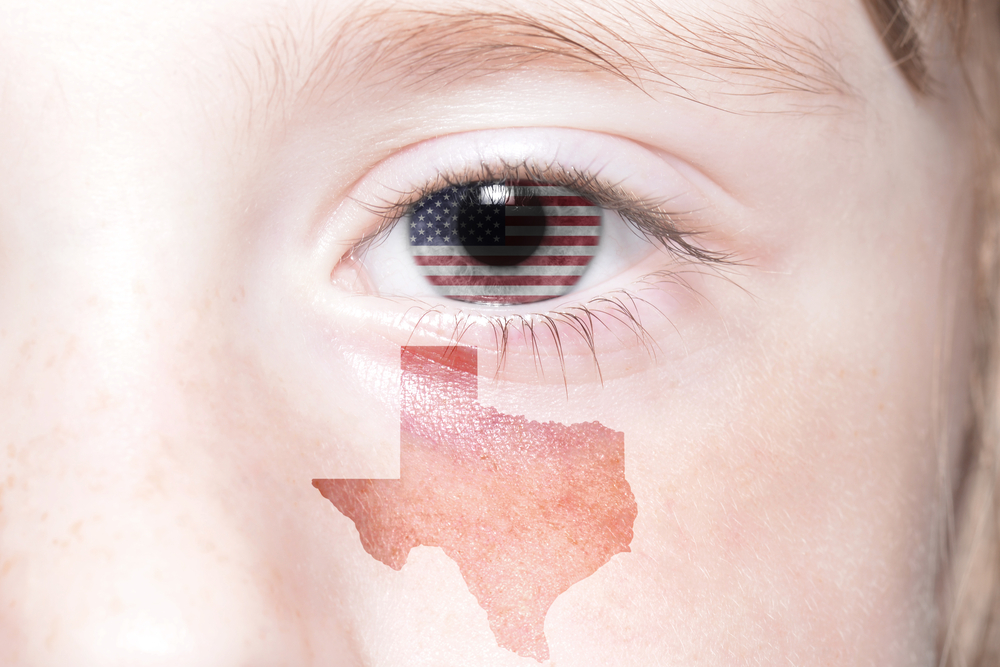 An eye with a Texas flag in the iris and a reddish tattoo of the state of Texas under the eye