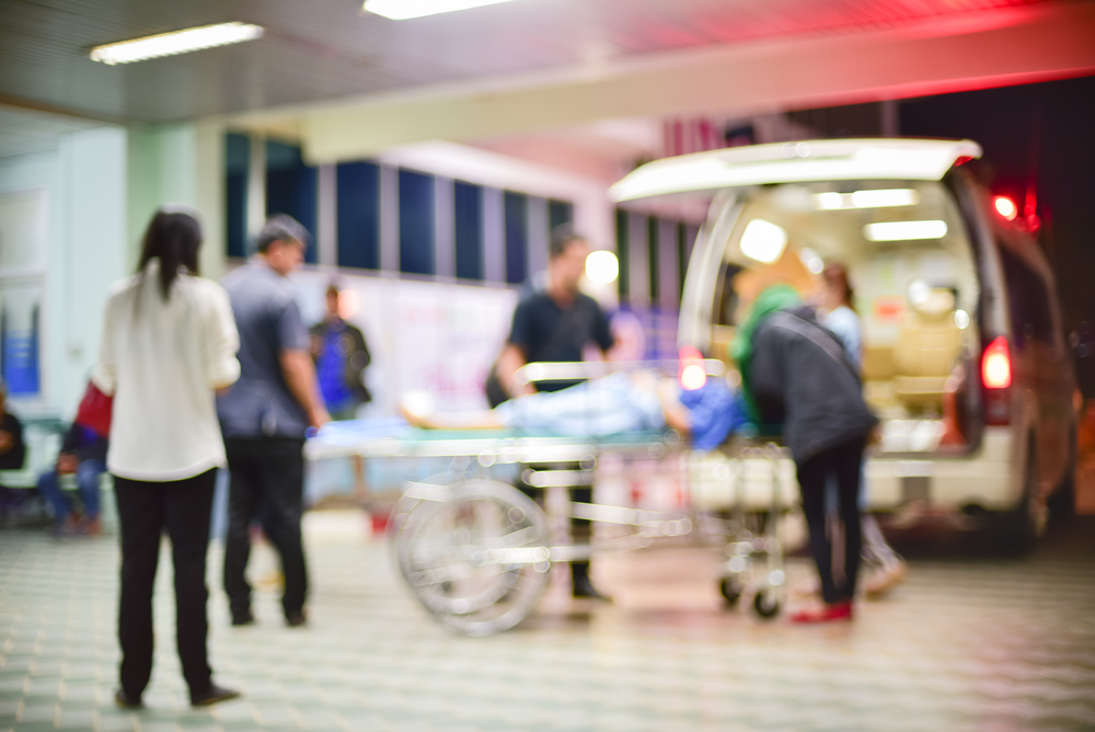 A patient emergency being handled by a team of medical professionals in front of an ambulance.