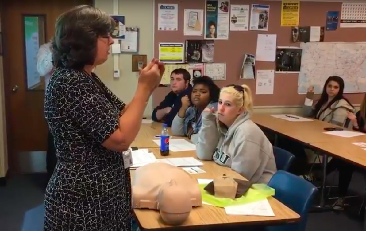 Teacher showing college students how to administer Narcan.