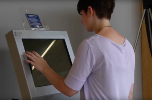 A student demonstrating how to use the mental health screening kiosk.