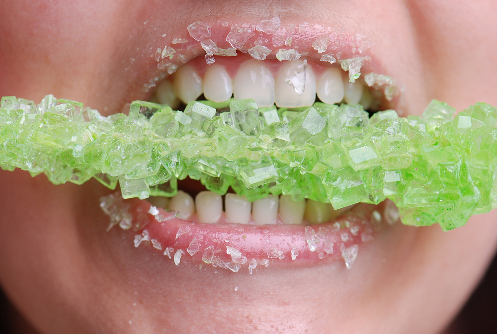 Close-up of a child eating green rock candy.