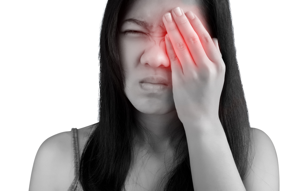Woman covers her inflamed eye with one of her hands.