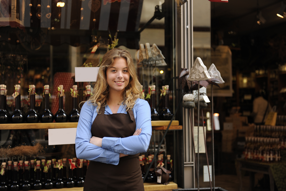 Female small business owner standing in front of store that sells alcohol.