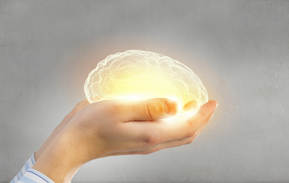 a hand holding a glowing brain.