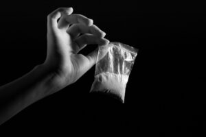 black and white image of a hand holding a bag of narcotics.