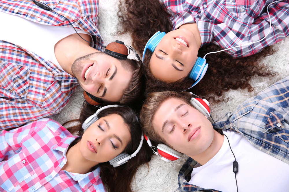 group of people lying on carpet and listening to music with headphones