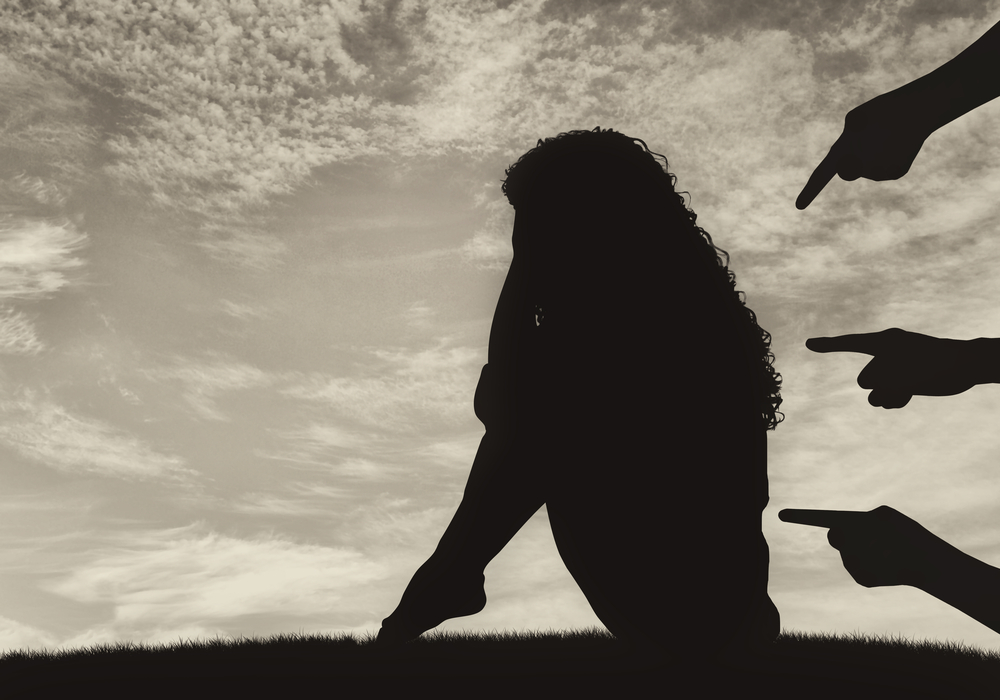 Sad woman getting pointed at by 3 hands