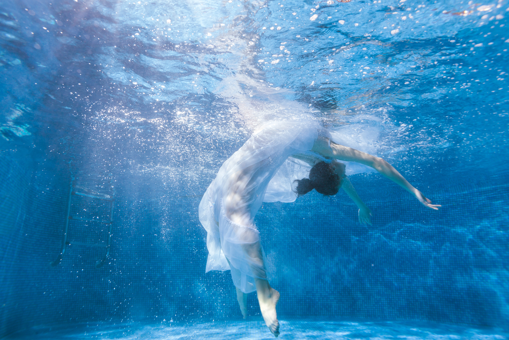 Woman in flowy dress swimming underwater