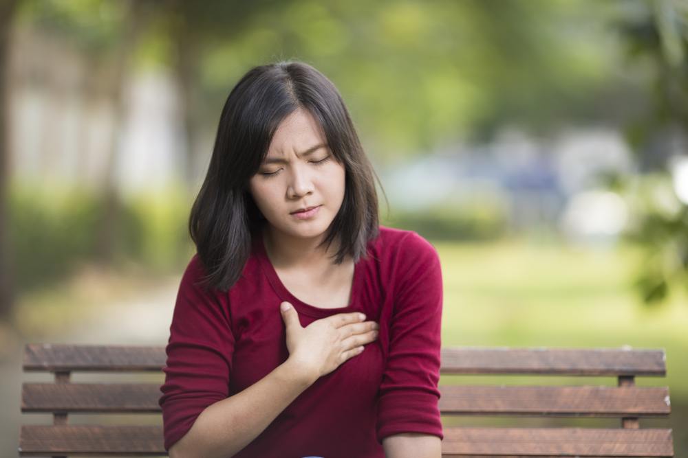 A woman on a bench with her hand over her heart.