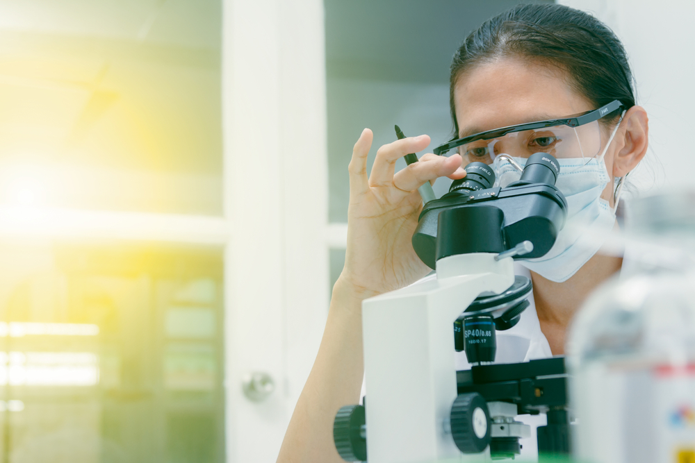 female scientist looking into microscope in a clinical laboratory