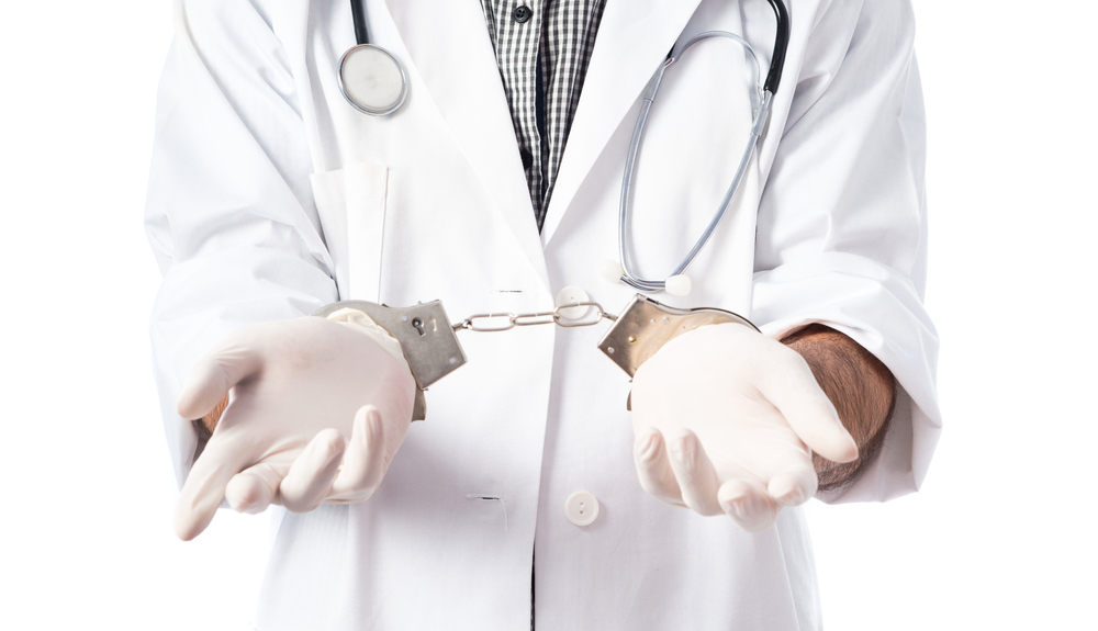 handcuffed doctor in white lab coat