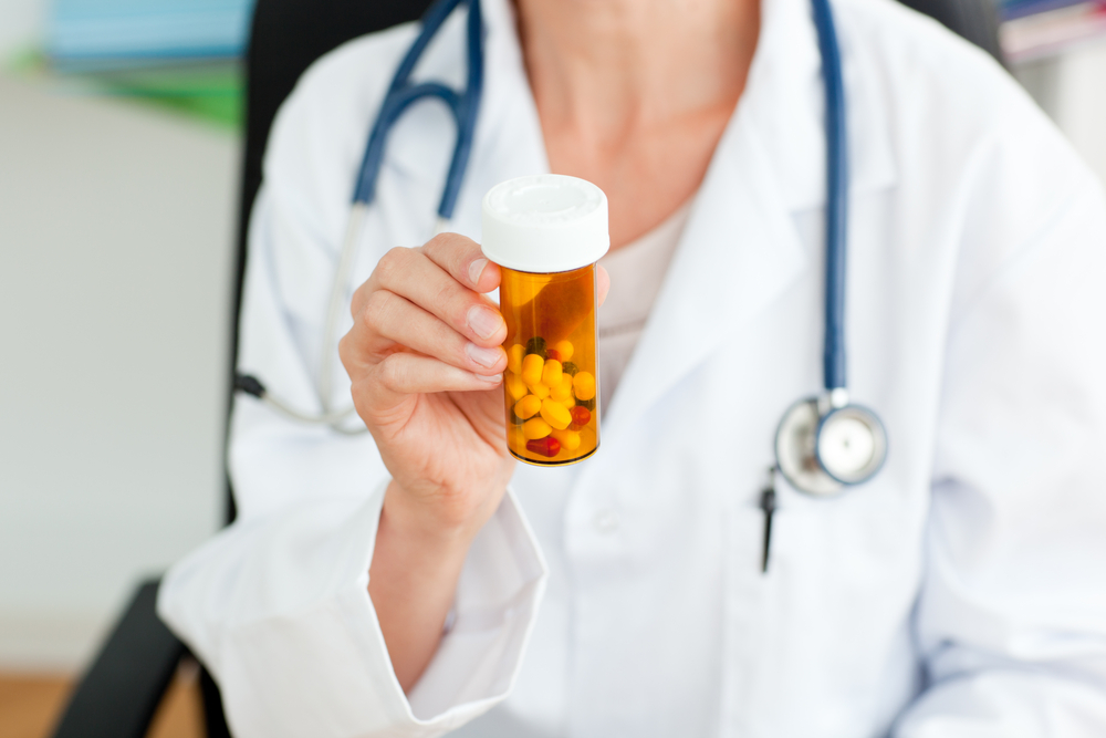 Close-up of a female doctor holding a bottle of pills.