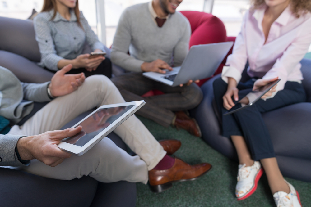 Group of people sitting with electronic devices.