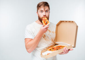 Man eating a slice of pizza out of the box.