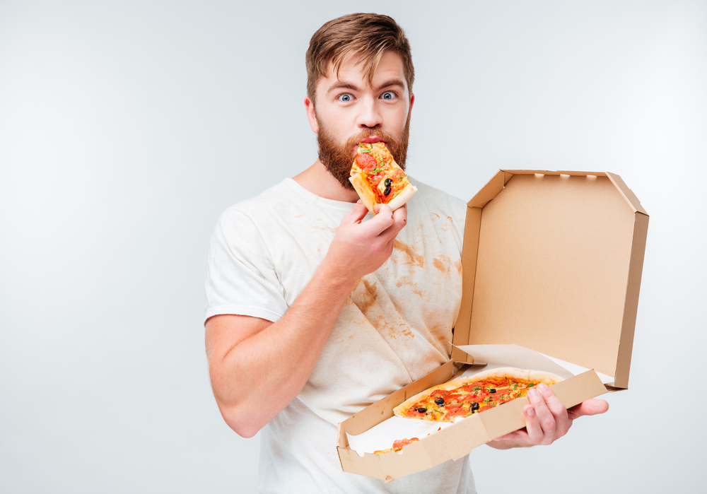 Man eating a slice of pizza out of the box.