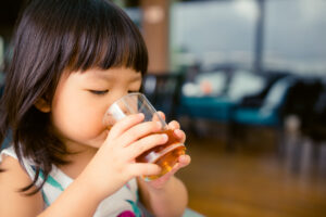 Small child drinking apple juice at a restaurant.