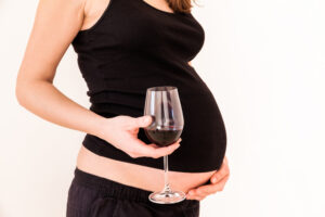 pregnant woman holding a glass of red wine.