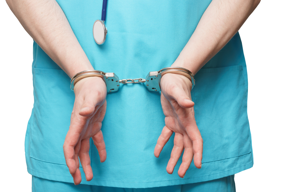 Doctor in blue uniform with stethoscope attached to handcuffed at the wrist