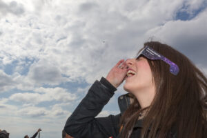 A woman viewing a solar eclipse wearing UV protective glasses