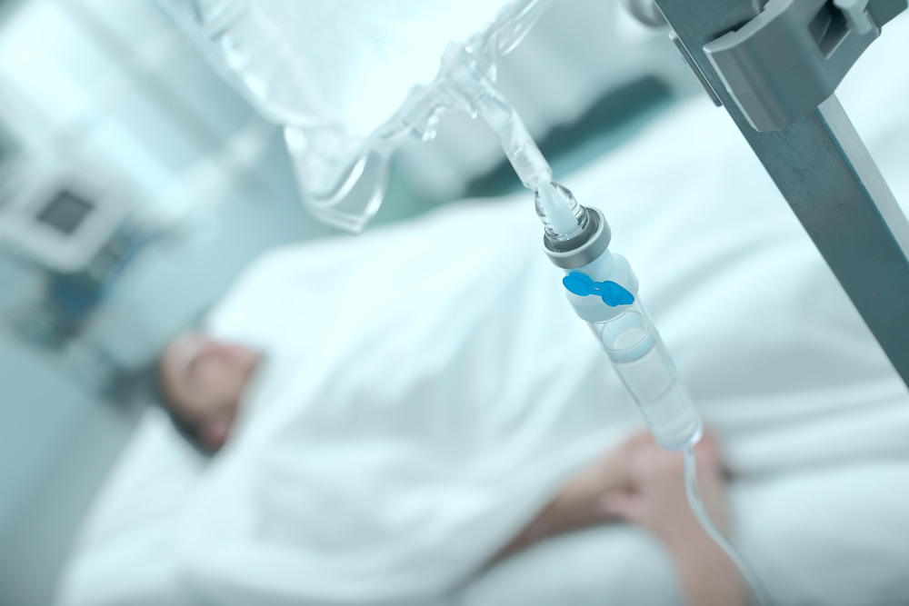 man in hospital bed with drip IV