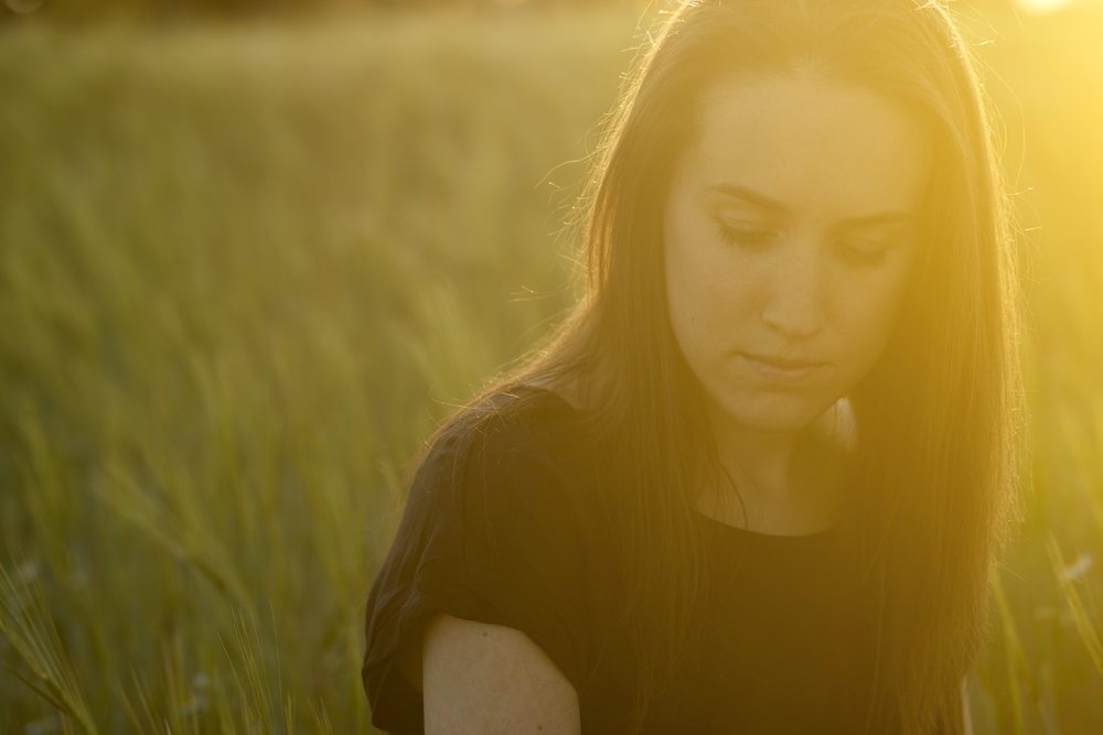 sad woman in field at dusk