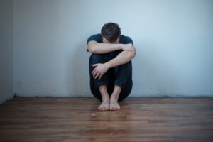 depressed man sitting hugging knees