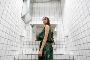 A woman in a restroom, looking behind her.