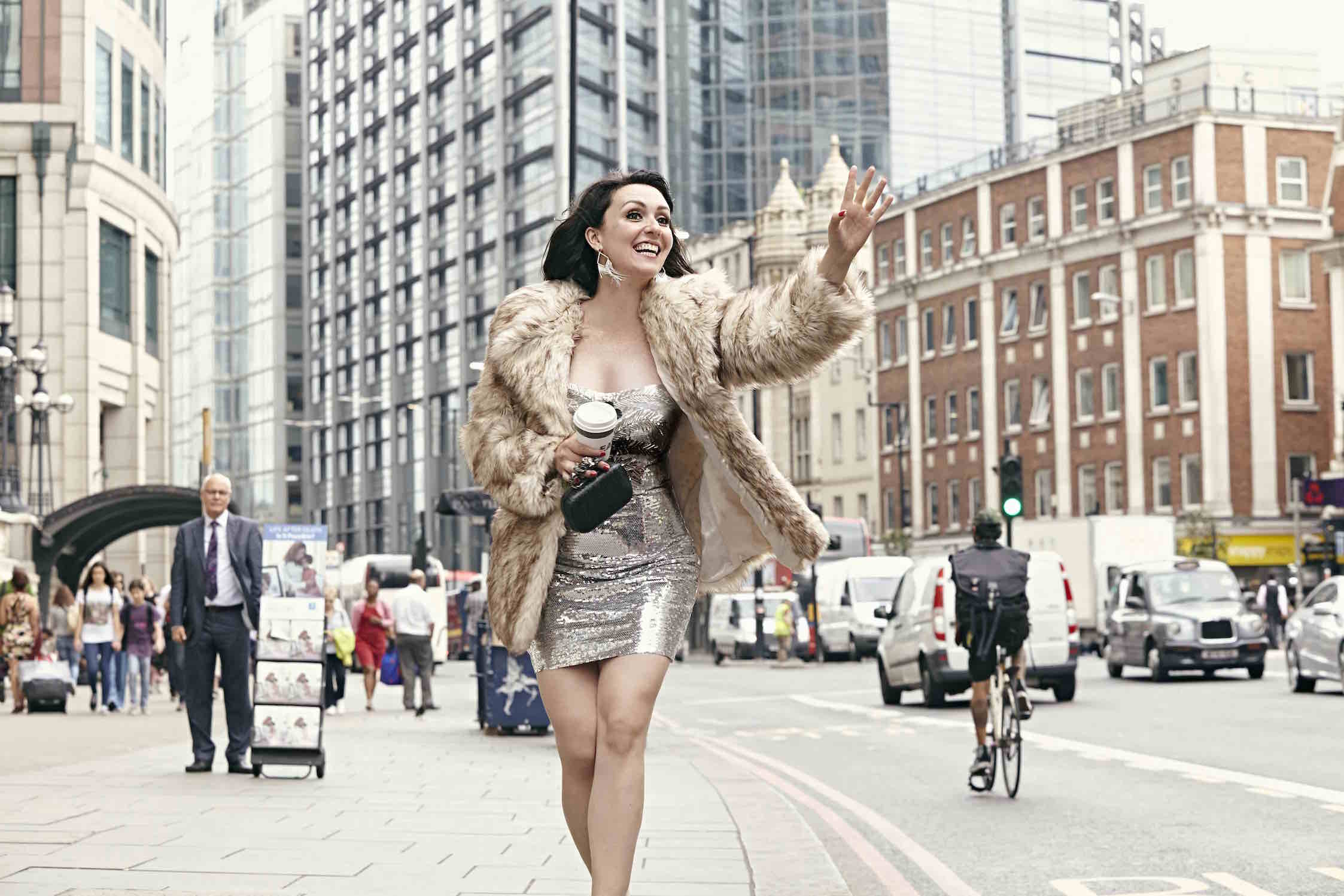Eleanor Conway walking down a busy sidewalk during the day in evening gown.