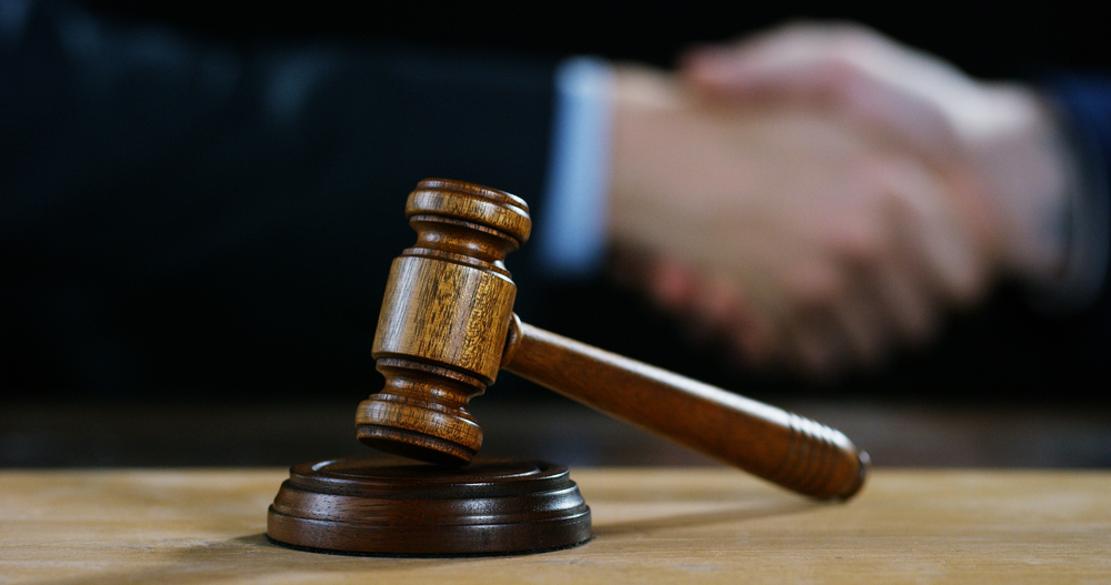 hands shaking in background; gavel in foreground